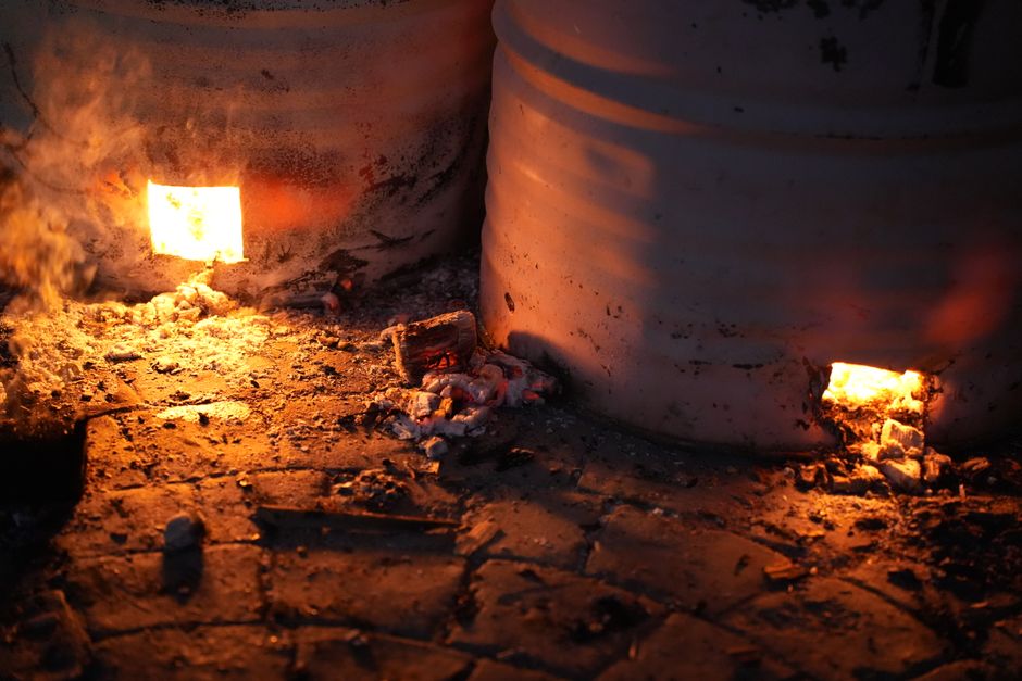 Warm glow of a kiln with visible embers and firelight shining through openings