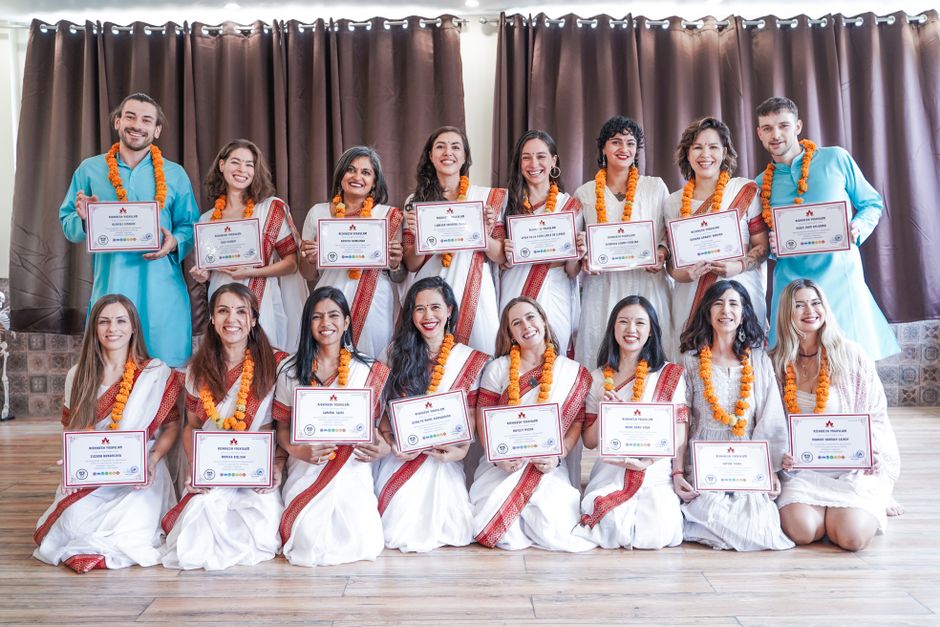 A diverse group posing with certificates in traditional attire at a graduation ceremony.