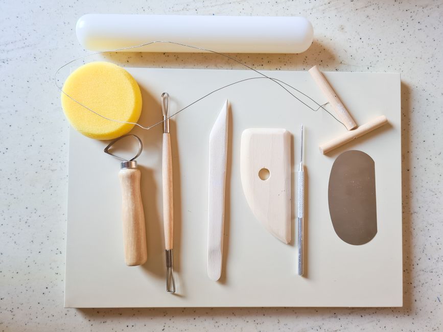 A top view of essential sculpting tools for clay art, arranged neatly on a board.